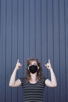 Portrait of a Girl in a protective mask free space for an inscription. Social distancing. Blue striped wall in the background