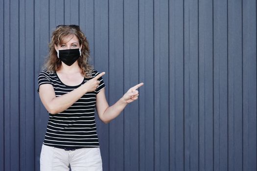 Portrait of a Girl in a protective mask free space for an inscription. Social distancing. Blue striped wall in the background