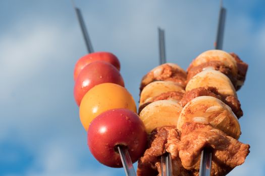 Marinated raw meat for barbecue, barbecue or grill with onions and dressed vegetables on skewers, the photo against the sky. Cooking meat in the grill on skewers in nature in the summer on a picnic.