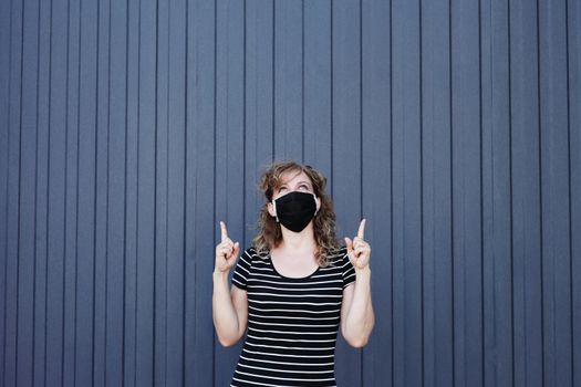 Portrait of a Girl in a protective mask free space for an inscription. Social distancing. Blue striped wall in the background