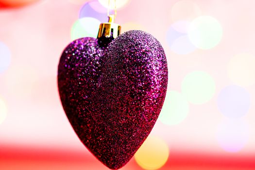 Heart shaped Christmas decoration isolated on blurred background of lights.