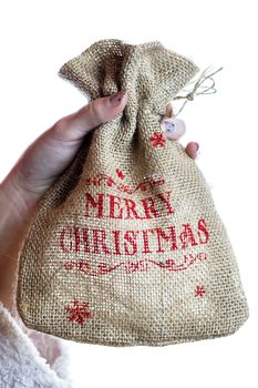 Hand holding Christmas burlap sack isolated on white background