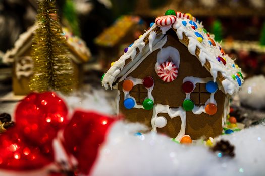 Colorful gingerbread house isolated on blurred background with Christmas decoration.