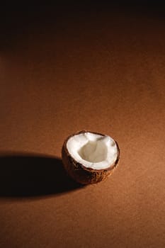 Single coconut fruit on brown plain background, abstract food tropical concept, angle view copy space