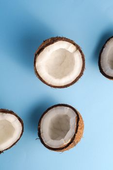 Coconut fruits on blue vibrant plain background, abstract food tropical concept, top view