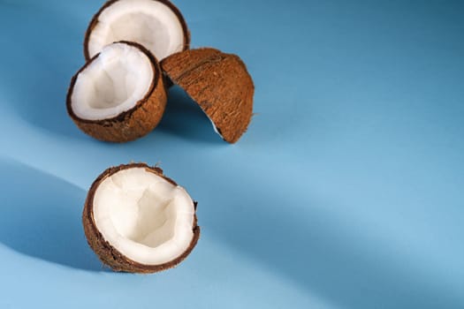 Coconut fruits on blue vibrant plain background, abstract food tropical concept, angle view copy space