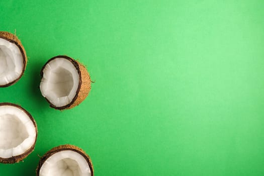 Coconut fruits on green plain background, abstract food tropical concept, top view copy space