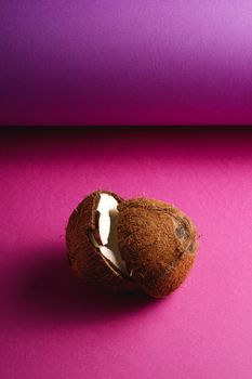 Coconut fruits on purple violet folded paper background, abstract food tropical concept, angle view copy space