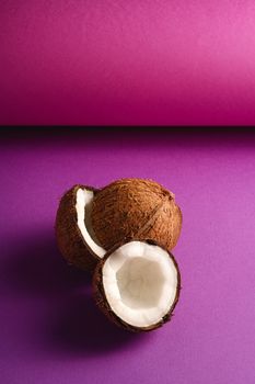 Coconut fruits on purple violet folded paper background, abstract food tropical concept, angle view copy space