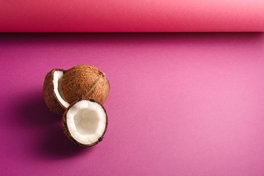 Coconut fruits on vibrant pink purple folded paper background, abstract food tropical concept, copy space angle view