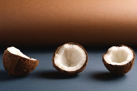 Coconut fruits on brown and blue grey folded paper background, abstract food tropical concept, angle view copy space