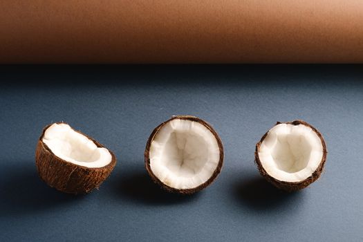 Coconut fruits on brown and blue grey folded paper background, abstract food tropical concept, angle view copy space