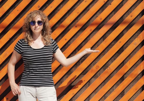 Woman portrait in sunglasses, free space for inscription. Orange wooden wall in the background