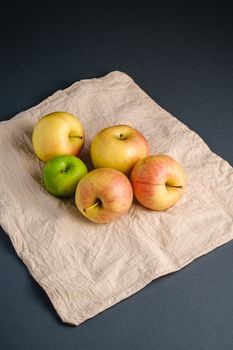 Fresh sweet apples on reusable textile grocery bag on dark grey background, angle view