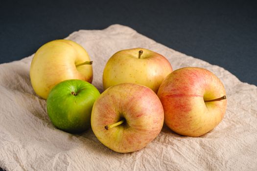 Fresh sweet apples on reusable textile grocery bag on dark grey background, angle view close up