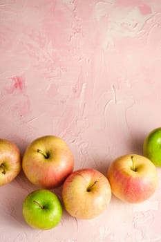 Fresh sweet apples on pink textured background, top view copy space
