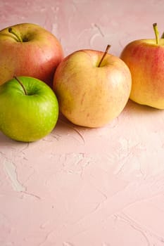 Fresh sweet apples on pink textured background, angle view copy space