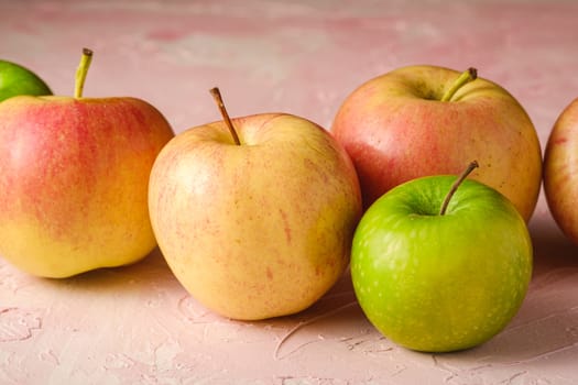 Fresh sweet apples on pink textured background, angle view macro