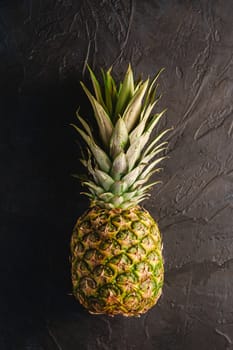 Fresh sweet pineapple on dark black textured background, top view copy space