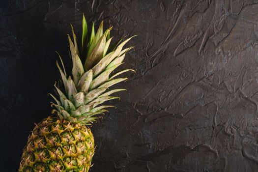 Fresh sweet pineapple on dark black textured background, top view copy space