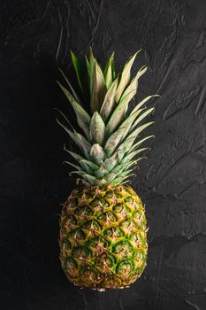 Fresh sweet pineapple on dark black textured background, top view copy space