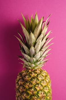 Fresh sweet pineapple on pink purple background, top view, cropped