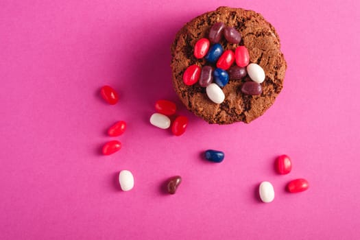 Homemade oat chocolate cookies stack with cereal with juicy jelly beans on minimal pink purple background, top view