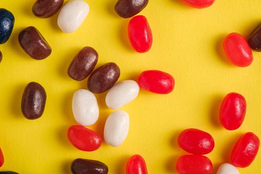 Juicy sweet fruit colorful jelly beans on bright yellow background, top view macro