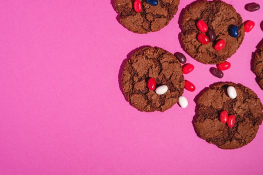 Homemade oat chocolate cookies with cereal with juicy jelly beans on minimal pink purple background, top view copy space