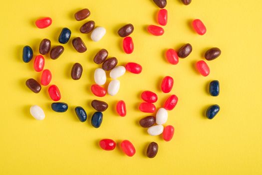 Juicy sweet fruit colorful jelly beans on bright yellow background, top view