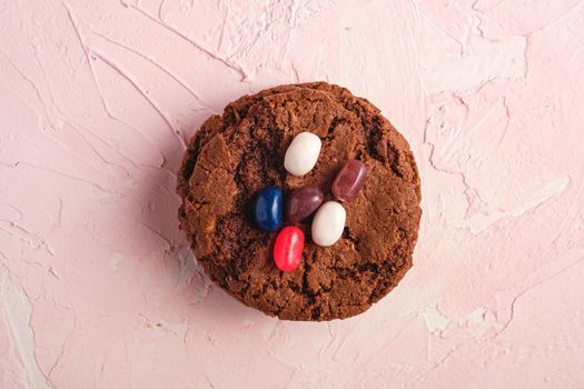 Homemade oat chocolate cookies stack with cereal with juicy jelly beans on textured pink background, top view