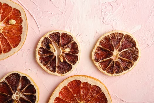 Dried lemon and grapefruit slices, citrus fruits on pink textured background, top view