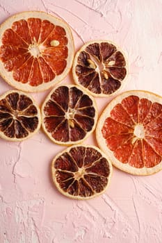 Dried lemon and grapefruit slices, citrus fruits on pink textured background, top view