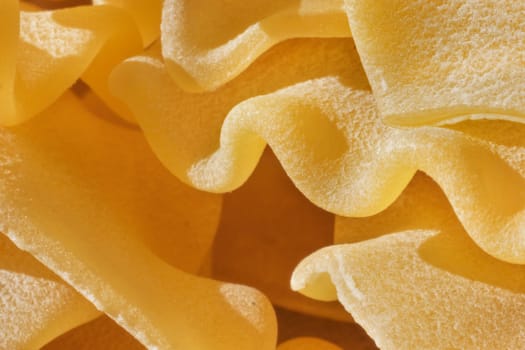 Dry Italian pasta called pantacce  close up ,rhombus -shaped pasta with wavy edge ,funny composition , studio shot , front view , high contrast