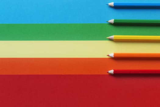 Different colored pencils on a multicolored background.A horizontal and graphic composition,rainbow effect