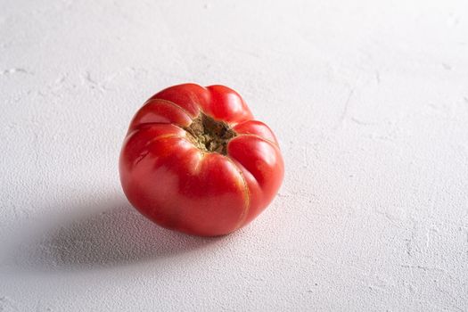 One pink heirloom tomato vegetable, fresh red ripe tomatoes, vegan food, white stone concrete background, angle view macro