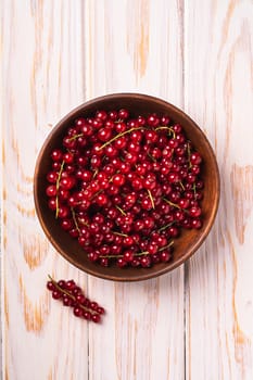 Fresh sweet red currant berries in wooden bowl, wood table background, top view