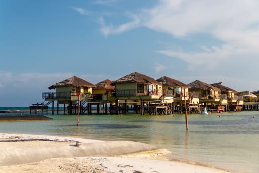 Water Villas (Bungalows) and wooden bridge at Tropical beach in the Caribbean sea at summer day