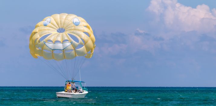 Yellow wing with happy face from skydiving pulled by a boat. Summer maritime recreation