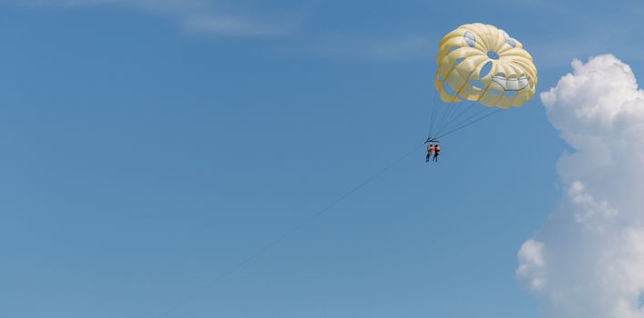 Yellow wing with happy face from skydiving pulled by a boat. Summer maritime recreation