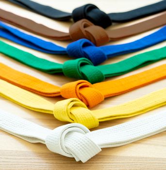 Martial arts colored belts on a wood background. From white to black belt.