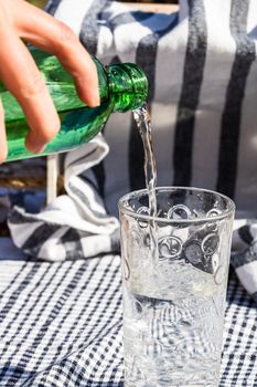 Pouring water from green bottle into a glass