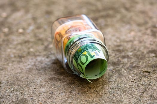 Composition with saving money banknotes in a glass jar. Concept of investing and keeping money, close up isolated.