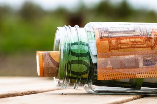 Composition with saving money banknotes in a glass jar. Concept of investing and keeping money, close up isolated.