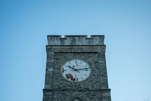 A Church's Cobblestone Clock Tower on a Clear Blue Sky