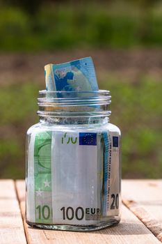 Composition with saving money banknotes in a glass jar. Concept of investing and keeping money, close up isolated.