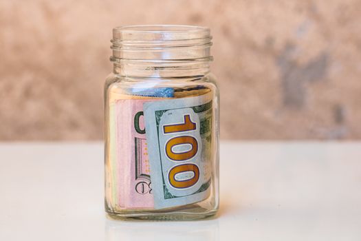 Composition with saving money banknotes in a glass jar. Concept of investing and keeping money, close up isolated.