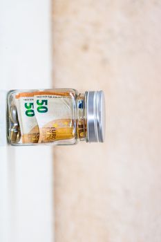 Composition with saving money banknotes in a glass jar. Concept of investing and keeping money, close up isolated.