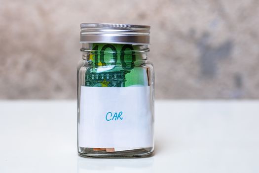 Composition with saving money banknotes in a glass jar with text new car .Concept of investing and keeping money, close up isolated.