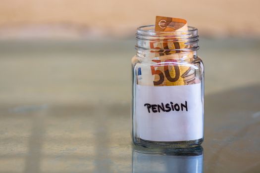 Composition with saving money banknotes in a glass jar with text pension .Concept of investing and keeping money, close up isolated.